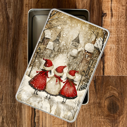 Metallic tin with Christmas-themed design of three figures in red and white outfits on a wooden surface