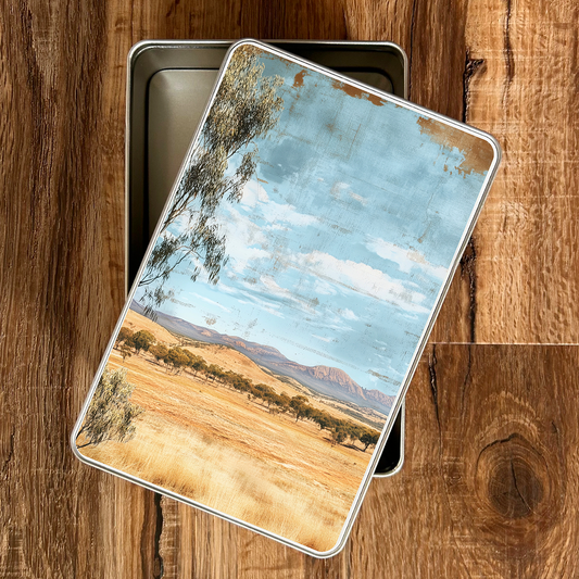 Metal tin with a scenic landscape design on a wooden surface