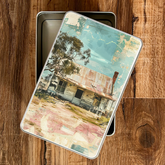 Metal tin with a vintage-style image of a Australian workmens cottage house on a wooden surface